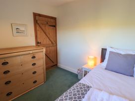A bedroom with a bed, chest of drawers, and a lamp at 2 Lupton Hall Cottages in Carnforth