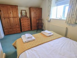 A bedroom with a bed and wooden furniture at 2 Lupton Hall Cottages in Carnforth