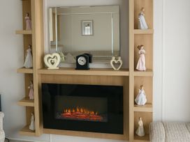 A living room with a fireplace and decorative items at Freshwater Beach Holiday Park - Holiday Accommodation 17116 in Burton Bradstock near Bridport