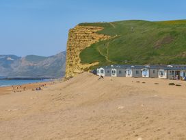 a beach along a coastline with cliffs and holiday accommodations at Freshwater Beach Holiday Park - Holiday Accommodation 17116 Burton Bradstock near Bridport