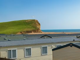 rooftops of caravans with a beach and cliff in the background at Freshwater Beach Holiday Park - Holiday Accommodation 17116 near Burton Bradstock