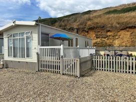A mobile home with a deck and fence at Freshwater Beach Holiday Park - Holiday Accommodation 17116 in Burton Bradstock near Bridport