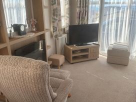 A living room with a television and armchair at Freshwater Beach Holiday Park - Holiday Accommodation 17116, Burton Bradstock near Bridport