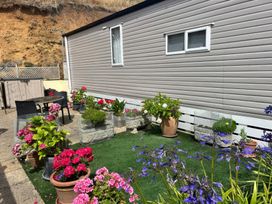 A garden area with a mobile home and flower pots at Freshwater Beach Holiday Park - Holiday Accommodation 17116 Burton Bradstock near Bridport