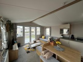 A living room with a couch and kitchen area at Trecco Bay - Holiday Accommodation 17447, Porthcawl