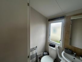A bathroom with a toilet, sink, and window at Trecco Bay - Holiday Accommodation 17447, Porthcawl