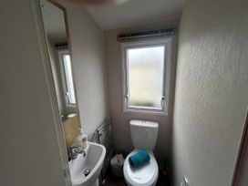 A bathroom featuring a toilet, sink, mirror, and radiator at Trecco Bay - Holiday Accommodation 17447, Porthcawl