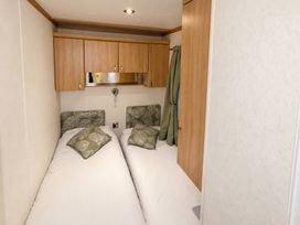 A bedroom with two beds and a mirror at Marsh Farm Holiday Park - Holiday Accommodation 17738, Great Yarmouth