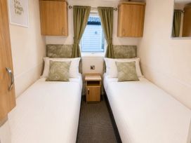 A bedroom with twin beds and a bedside table at Marsh Farm Holiday Park - Holiday Accommodation 17738, Great Yarmouth