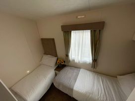 a bedroom with two single beds and a window with curtains at Golden Palm Resort - Holiday Accommodation 17870, Chapel St Leonard's