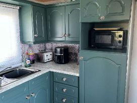 a kitchen with blue cabinets, a sink, a microwave, and a toaster at Hafan y Mor Haven - Holiday Accommodation 18358 in Pwllheli