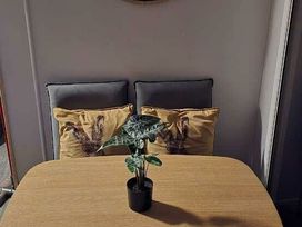 a dining table with a small plant and two decorative pillows at Hafan y Mor Haven - Holiday Accommodation 18358 in Pwllheli