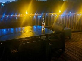 a deck with a table and chairs illuminated by string lights at Hafan y Mor Haven - Holiday Accommodation 18358 Pwllheli