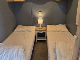 a bedroom with two single beds and a bedside table with a lamp at Hafan y Mor Haven - Holiday Accommodation 18358 in Pwllheli