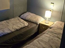 a small bedroom with two single beds and a lamp on a nightstand at Hafan y Mor Haven - Holiday Accommodation 18358, Pwllheli