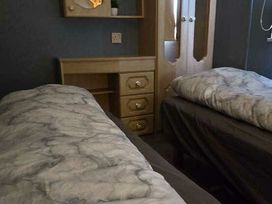 a bedroom with two single beds and a wooden bedside table at Hafan y Mor Haven - Holiday Accommodation 18358 in Pwllheli