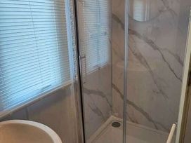 a bathroom with a glass shower enclosure and a white bath at Hafan y Mor Haven - Holiday Accommodation 18358, Pwllheli