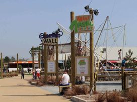 an outdoor recreational area with a climbing wall, trampoline, and aerial adventure attractions at Hafan y Mor Haven - Holiday Accommodation 18358, Pwllheli