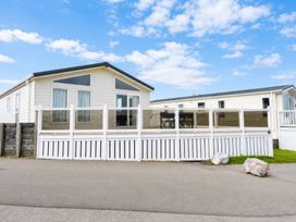 A mobile home with a deck and chairs at Trecco Bay - Holiday Accommodation 18462 in Porthcawl