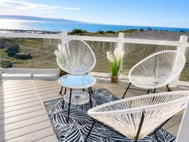 An outdoor patio with chairs and a table overlooking the sea at Trecco Bay - Holiday Accommodation 18462 Porthcawl
