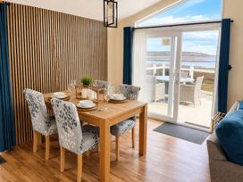 A dining table with chairs and a view of the outdoors at Trecco Bay - Holiday Accommodation 18462 Porthcawl