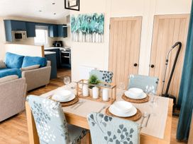 A dining room with a table set for four at Trecco Bay - Holiday Accommodation 18462 Porthcawl