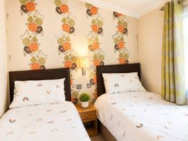 A bedroom with two beds and floral wallpaper at Trecco Bay - Holiday Accommodation 18463, Porthcawl