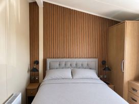 A bedroom with a bed and wood paneling at Trecco Bay - Holiday Accommodation 18463, Porthcawl