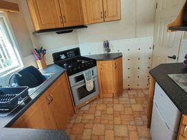 a kitchen with wooden cabinets and a gas stove at Promenade Site - Holiday Accommodation 18601 in Ingoldmells