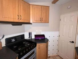 a kitchen with wooden cabinets and a gas stove at Promenade Site - Holiday Accommodation 18601 in Ingoldmells