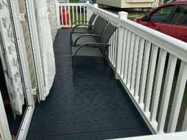 a deck with two chairs and a railing at Promenade Site - Holiday Accommodation 18601 in Ingoldmells