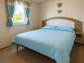 a bedroom with a bed featuring light blue bedding and curtains at Marton Mere Holiday Village - Holiday Accommodation 18682, Blackpool