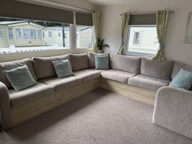 A living room with a corner sofa and large windows at Shorefield Country Park - Holiday Accommodation 18837 Lymington
