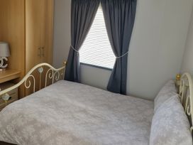 A bedroom with a bed and wardrobe at Millers Cottage Caravan Park - Holiday Accommodation 18845, Towyn, Abergele