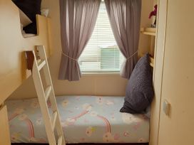 A bedroom with a bunk bed and a window at Millers Cottage Caravan Park - Holiday Accommodation 18845, Towyn, Abergele