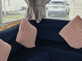 A living room with a couch and pillows at Millers Cottage Caravan Park - Holiday Accommodation 18845 Towyn, Abergele