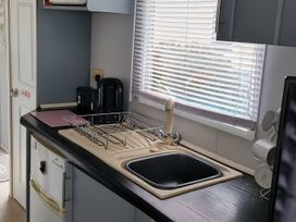 A kitchen with a sink and dish rack at Millers Cottage Caravan Park - Holiday Accommodation 18845, Towyn, Abergele