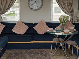 A living room with a sofa and dining table at Millers Cottage Caravan Park - Holiday Accommodation 18845, Towyn, Abergele