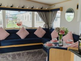 A living room with a blue sofa and pink pillows at Millers Cottage Caravan Park - Holiday Accommodation 18845, Towyn, Abergele