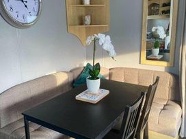a dining area with a round clock, a table, chairs, and an orchid plant at Seaview Caravan Park - Holiday Accommodation 18903 in Ingoldmells