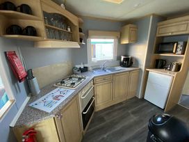 a kitchen with cabinets, a sink, an oven, and a refrigerator at Seaview Caravan Park - Holiday Accommodation 18903 in Ingoldmells
