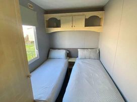 a bedroom with two single beds and a shelf above at Seaview Caravan Park - Holiday Accommodation 18903 in Ingoldmells