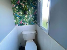a bathroom with a toilet and tropical-themed wallpaper at Seaview Caravan Park - Holiday Accommodation 18903 in Ingoldmells