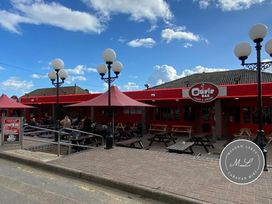 an outdoor seating area with umbrellas and picnic tables at the Oasis Bar in Ingoldmells