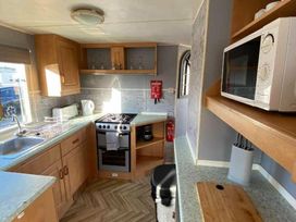 a kitchen with wooden cabinets and a gas stove at Seaview Caravan Park - Holiday Accommodation 18905 in Ingoldmells