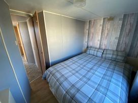 a bedroom with a double bed and patterned wallpaper at Seaview Caravan Park - Holiday Accommodation 18905 in Ingoldmells