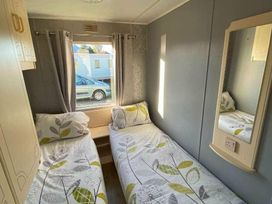 a bedroom with two single beds and a mirror at Seaview Caravan Park - Holiday Accommodation 18905 in Ingoldmells