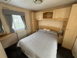a bedroom with a double bed and wooden furniture at Seaview Caravan Park - Holiday Accommodation 18940 in Ingoldmells