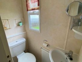 a bathroom with a toilet, sink, mirror, and a window at Seaview Caravan Park - Holiday Accommodation 18940 in Ingoldmells