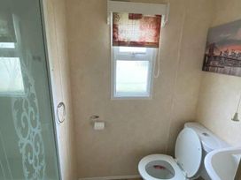 a bathroom with a shower, toilet, and window at Seaview Caravan Park - Holiday Accommodation 18940 in Ingoldmells